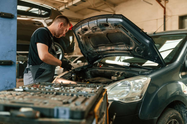 Under the hood. Man is works in the automobile repairing salon Under the hood. Man is works in the automobile repairing salon. mechanic working under car stock pictures, royalty-free photos & images