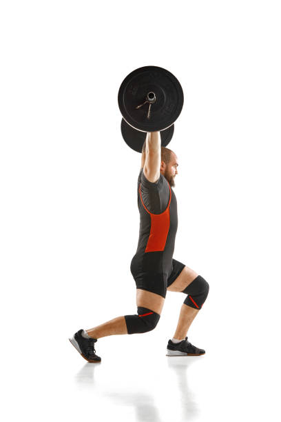 istock Side view. Muscular, athletic man, weightlifter training, lifting heavy barbell against white background 1820069106
