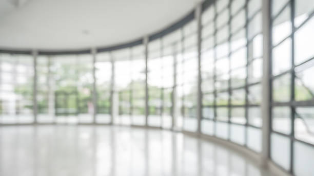 istock Office building lobby hall blur background or blurry school hallway corridor interior view looking toward empty corridor entrance, glass curtain wall and floor with exterior light illumination 1820069636