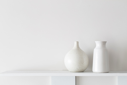 white ceramic vases on wooden shelf on white wall