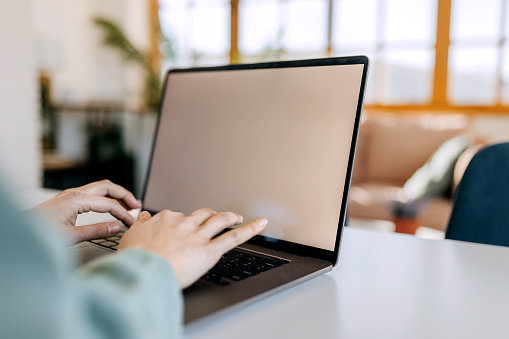 Close up shot of woman using laptop with blank screen at home