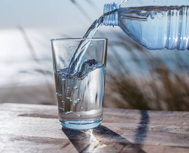 istock Pouring water into a glass from plastic bottle. Nature background. 1820084678