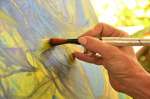 istock A painters hand painting yellow on a canvas 182008843