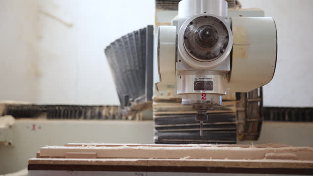 CNC machine processes wood in furniture factory