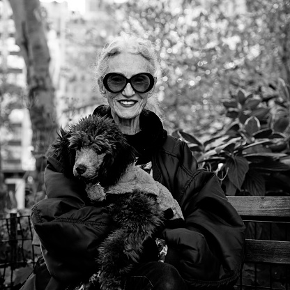 Happy senior woman posing with her dog in Madison Square Park, New York City