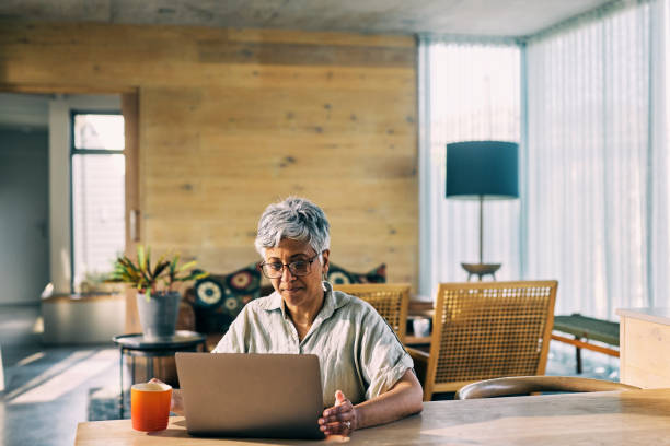 istock Smiling Generation X African-American Woman Enjoying Retirement While Using Laptop in a Sunny Home Interior 1820110490