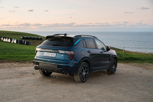 Cobreces, Spain - 23 November 2023: A Lynk & Co 01 electric SUV car in a natural area by the sea at sunset