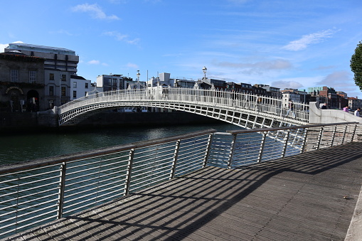 Dublin, Ireland – September 20, 2021: 19th century Ha'penny Bridge pedestrian bridge over the River Liffey from Liffey Boardwalk