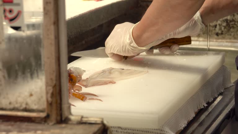 Chef cutting fresh squid on a cutting board