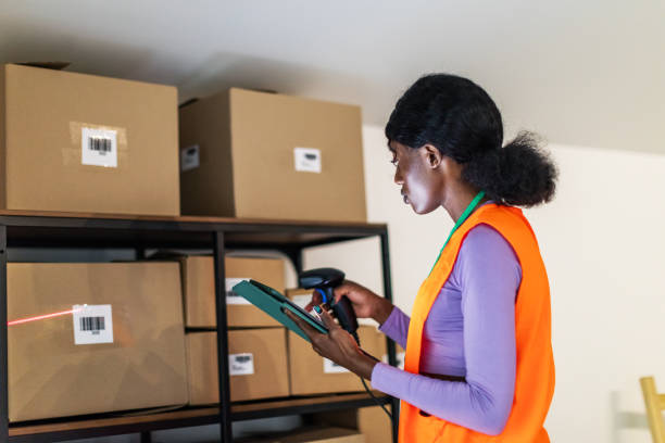 istock Young adult black woman scanning package using barcode reader and digital tablet at warehouse 1820245887