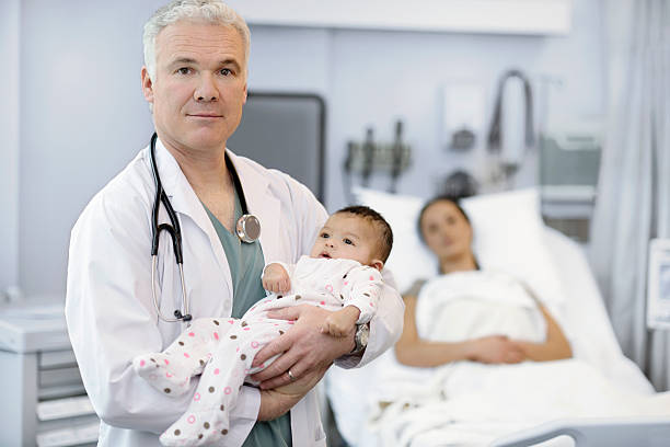 Male doctor with baby girl and mother stock photo
