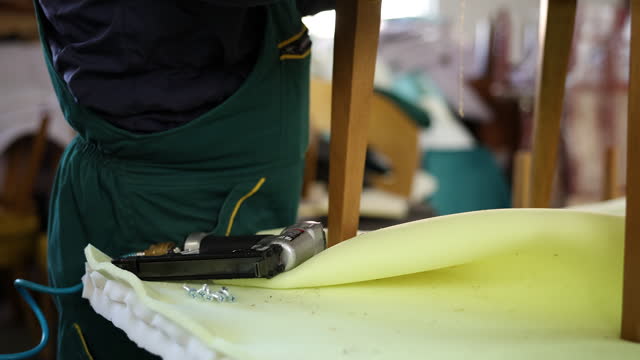Technician works with staple gun in furniture workshop