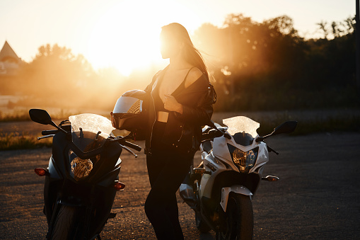 Between two vehicles, against smoke. Woman is with motorcycle outdoors.