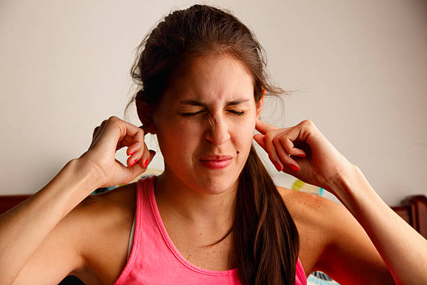 Young woman disturbed by loud noise pollution stock photo