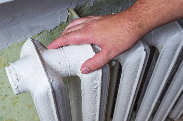 istock Male hand touching cast iron radiator. House heating. 1820259152