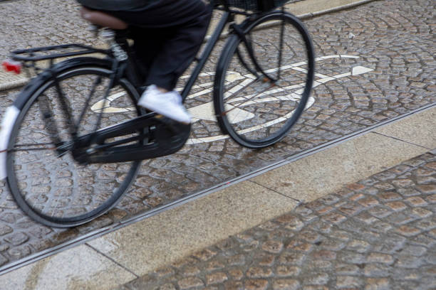 A golden circular plaque with a bicycle icon set into grey cobblestone pavement in Bruges, evoking urban transport, bike-friendly infrastructure, and eco-friendly city design.