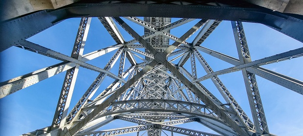Photo of a structure of steel girders of a bridge in front of a blue sky during the day