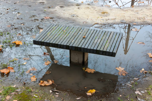 A puddle and dirt under a bench is a problem of infrastructure and improvement in the city stock photo