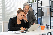 Female manager looking very angry showing employee her mistakes on laptop