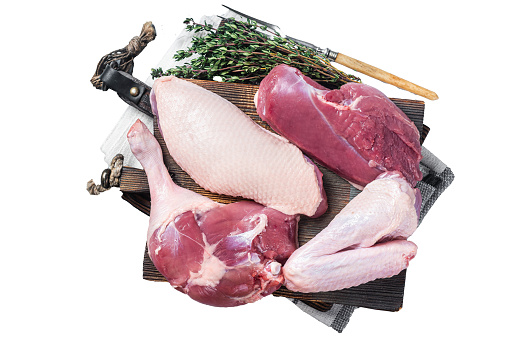 Butchered whole duck, raw breast steak, legs, wings on a butcher cutting board.  Isolated, white background