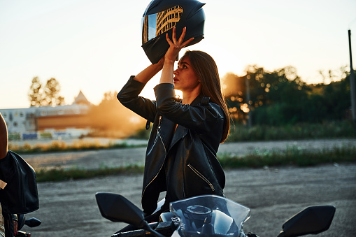 Standing and wearing the helmet. Two women on motorcycles are together outdoors.