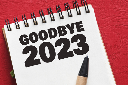 GOODBYE 2023 text in an office notebook on a red table.