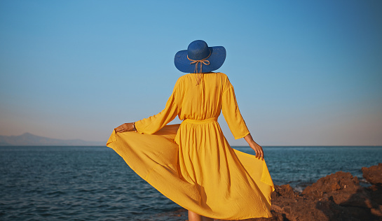 Woman in yellow dress against the ocean.