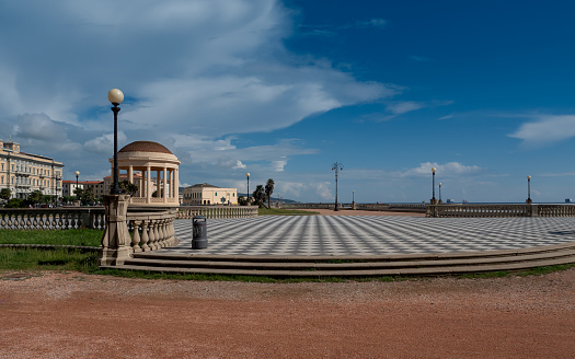 LIVORNO, ITALY - JUNE 5, 2023: The chequered black and white pavement of the Terrazza Mascagni in Livorno under a blue sky with scattered clouds