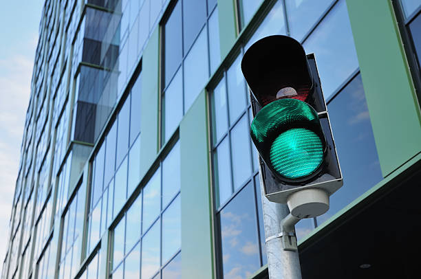 Close-up of a green traffic light Green light on and red light off on a traffic signaling system that allows cars to get into an underground carpark underneath the business center  green light stoplight photos stock pictures, royalty-free photos & images