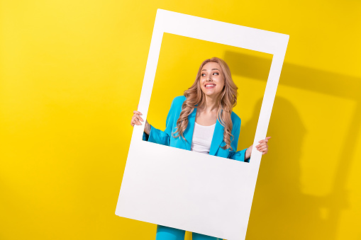 Photo of lovely positive person hold paper album card look empty space isolated on yellow color background.