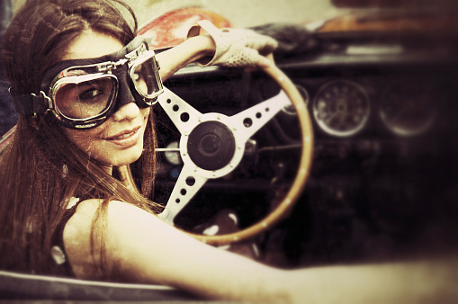 Woman in a vintage car. Texture and age effects added. Tilt and shift effect.