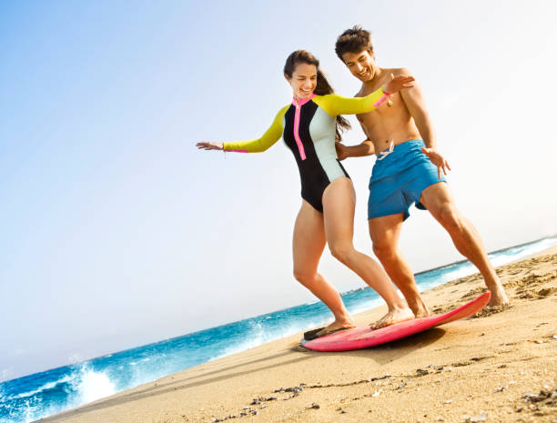 istock Man teaching woman to surfboard on beach 182027525