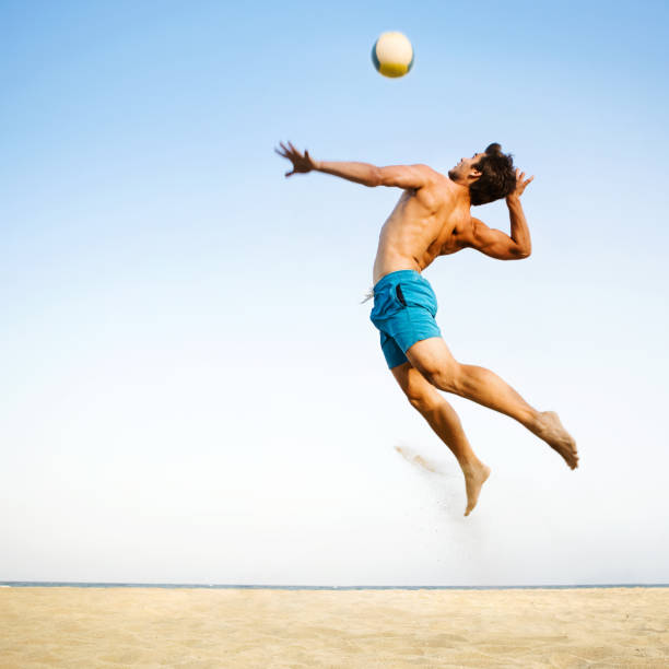 Beach volleyball Male beach volleyball player jumping up to spike ball beach volleyball stock pictures, royalty-free photos & images