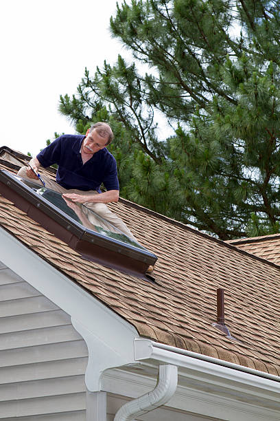 istock Home inspector on a roof examins a residential skylight. 182027645