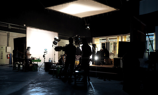 Making of movie video in big production studio and film crew team shooting or recording by professional digital camera and lighting set equipment.