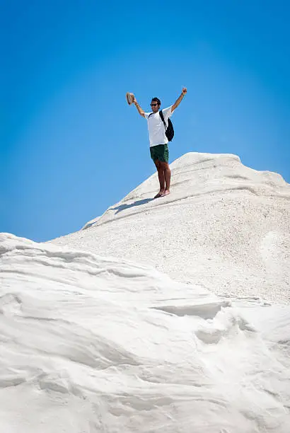 Photo of Young adult man rejoices on top of a white mountain
