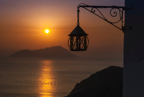 Sunset in Milos, Cyclades Islands, Greece. Focus on a classic lantern in the foreground.