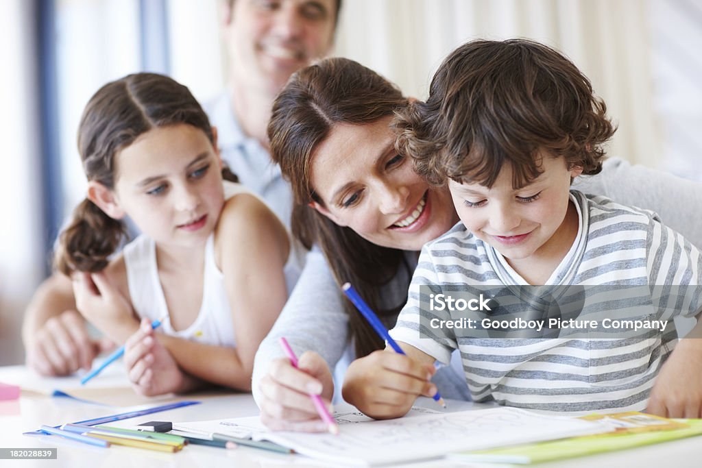 Participating in their children's education A young boy drawing as his family watches with great interest Child Stock Photo