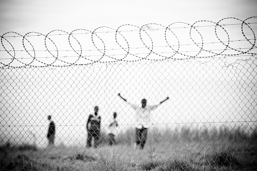 Arms spread searching for freedom behind a barbed wire fence