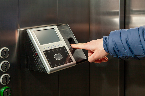 The man put his finger in the Fingerprint Access Control Terminal with face recognition function installed in the elevator of the business center, which tracks attendance in real time