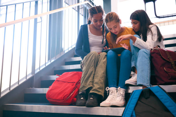 istock Three Female Secondary Or High School Pupils Inside School Building On Stairs With Digital Tablet 1820294613