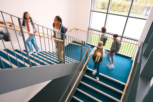 Group Of Secondary Or High School Pupils Inside School Building On Stairs With Motion Blur