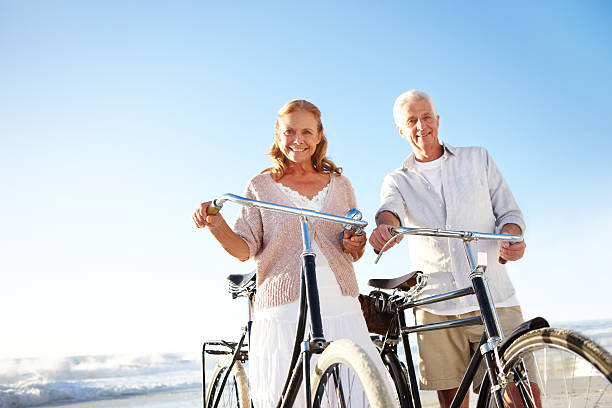 prêt à profiter d'un voyage à vélo - senior couple cycling beach bicycle photos et images de collection