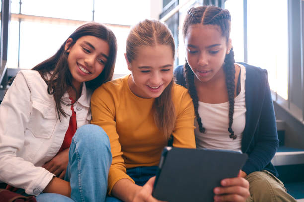 istock Three Female Secondary Or High School Pupils Inside School Building On Stairs With Digital Tablet 1820302010