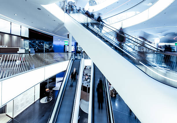 istock Shopping centre with moving people on escalators 182030369