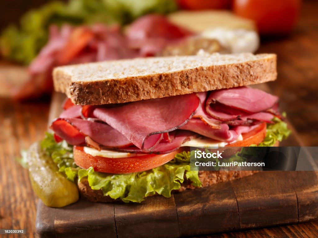 Pastrami Sandwich "Smoked Meat Sandwich with Lettuce, Tomato and Cheese on Whole Wheat Bread on a Cutting Board with all the Ingredients for Making it-Photographed on Hasselblad H3D2-39mb Camera" Sandwich Stock Photo