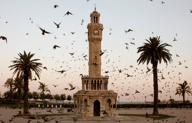 izmir clock tower surrounded by flock of birds at dusk - izmir stok fotoğraflar ve resimler