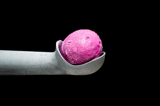 Special Metal Ice Cream Scoop with a Pink Ice Cream Ball on Top. Isolated on a Black Background.