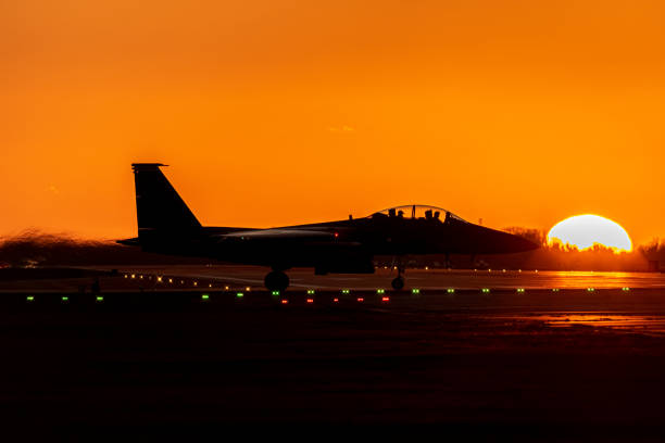 夕暮れ時に離陸前に滑走路に進入する軍用戦闘機のシルエット - pilot military air force cockpit ストックフォトと画像