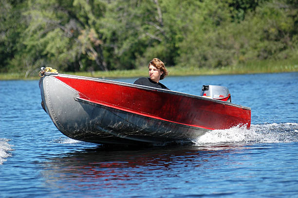 Cute Redhead Boy Fishing in Fishing Boat on the Lake in Autumn. Lac Saint-Joseph Lake, Fossambault-sur-le-Lac. The mountain is filled with colorful trees with autumn leaf colors. The little boy is smiling and is very happy.